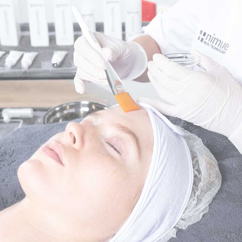 Women receiving Nimue facial with a beauty therapists brushing treatment over her forehead.