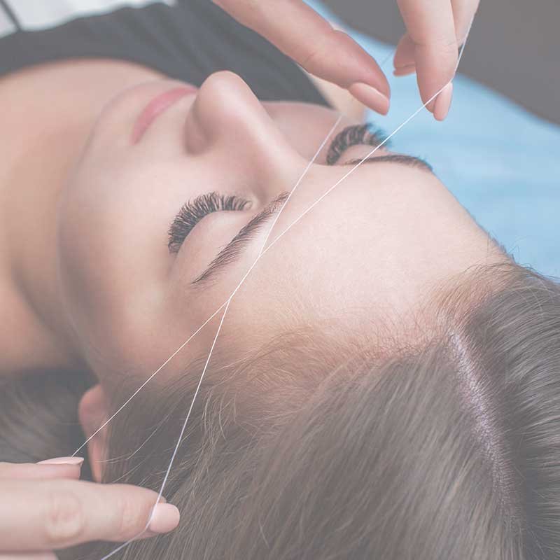 A beauty therapist threading a women eye brows